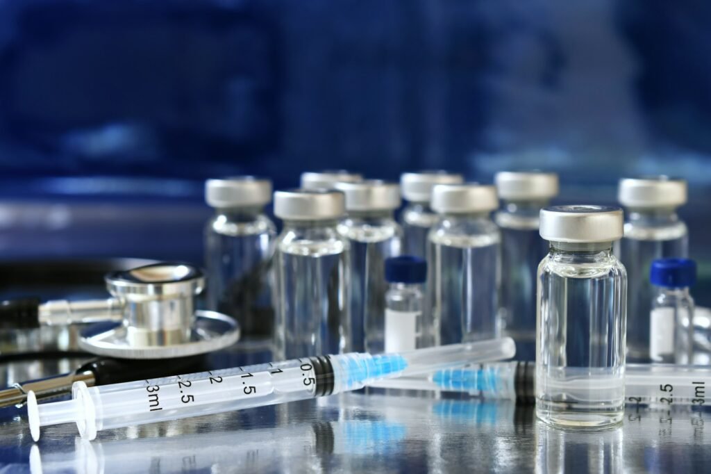 Vaccine booster concept background - vials of generic vaccines with syringe and stethoscope