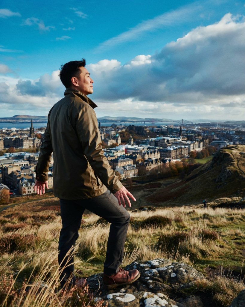 Person at the summit of Arthur’s Seat with the Edinburgh panorama behind