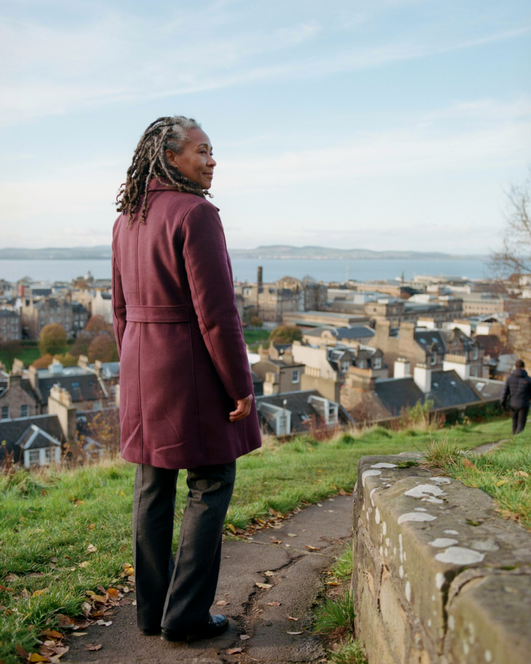 Person pausing on Calton Hill overlooking the Edinburgh skyline