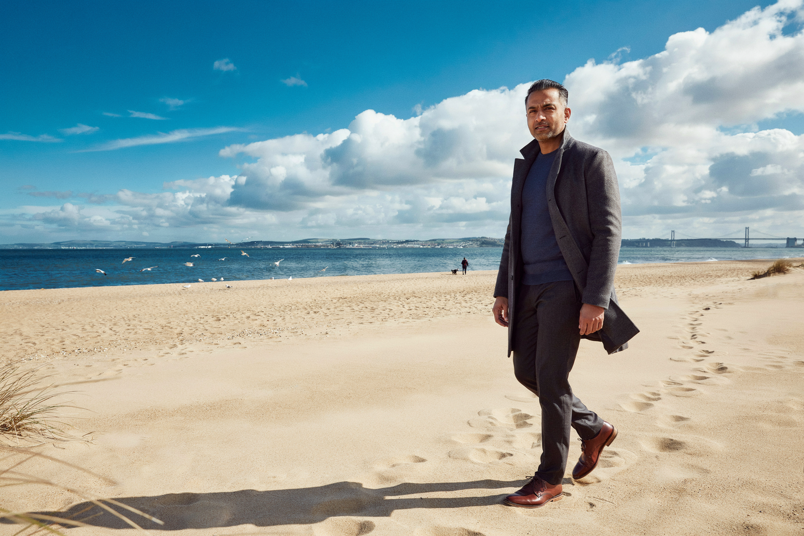 Person walking along Portobello Beach in Edinburgh with the Firth of Forth behind