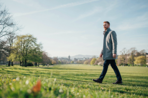 Person walking through the Meadows park in Edinburgh on a bright morning