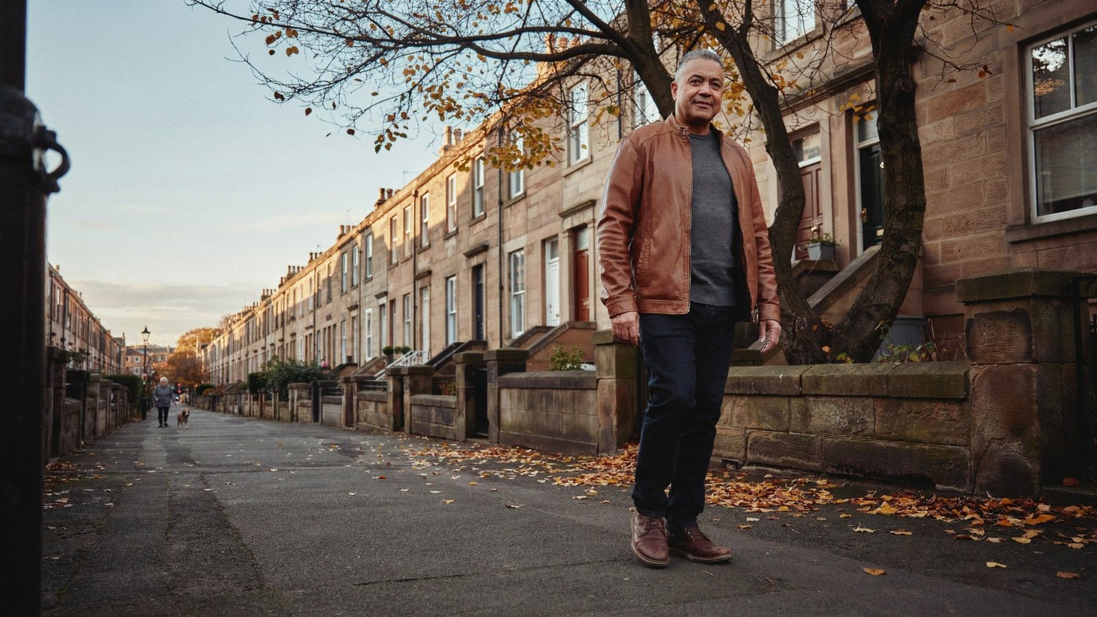 Adult walking along a quiet terraced street in the Stockbridge Colonies, Edinburgh, on a cold autumn afternoon during COVID-19 booster season