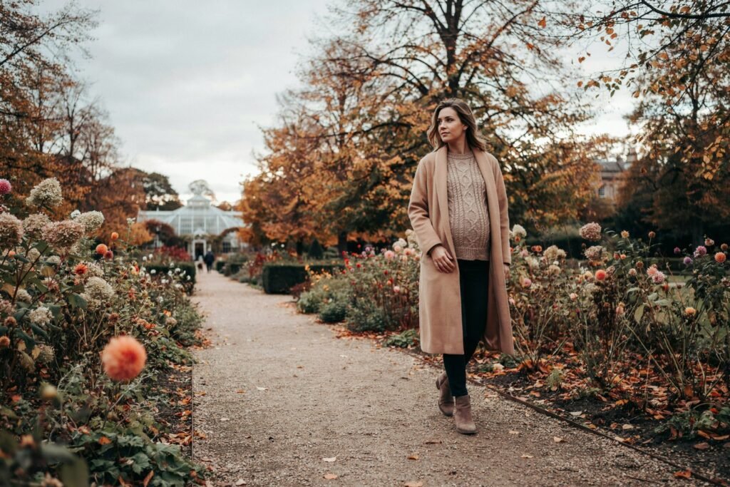 Pregnant woman walking through the gardens at Saughton Park in Edinburgh on a mild autumn afternoon, thinking about vaccination in pregnancy