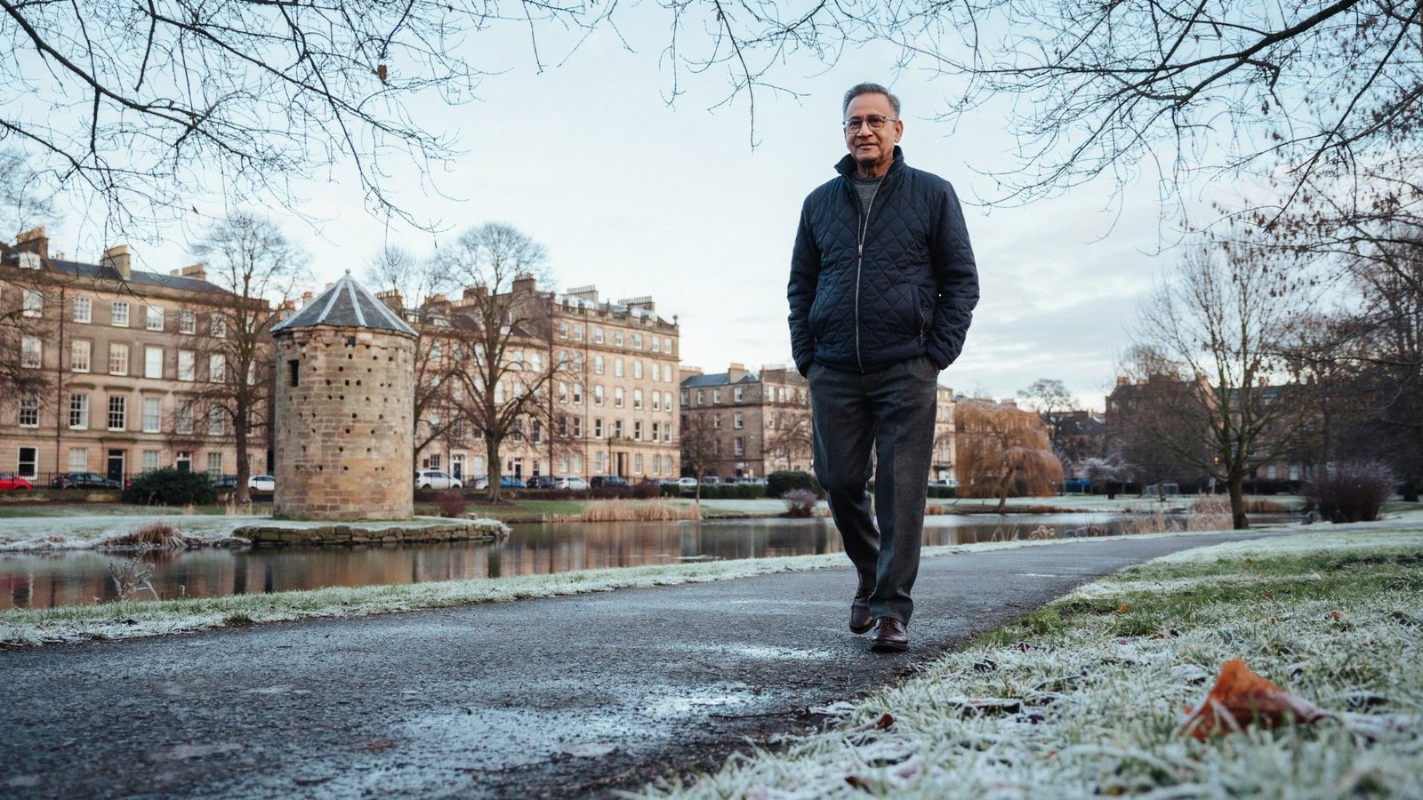 Older adult walking beside the loch in Lochend Park, Edinburgh, on a cold winter morning, protected by a COVID-19 vaccine timed around treatment