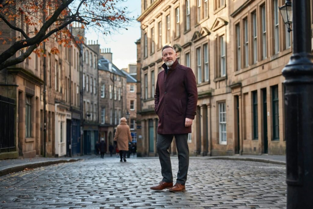 Older adult walking along the Royal Mile in Edinburgh on a crisp autumn morning, planning this winter's flu and Covid vaccines