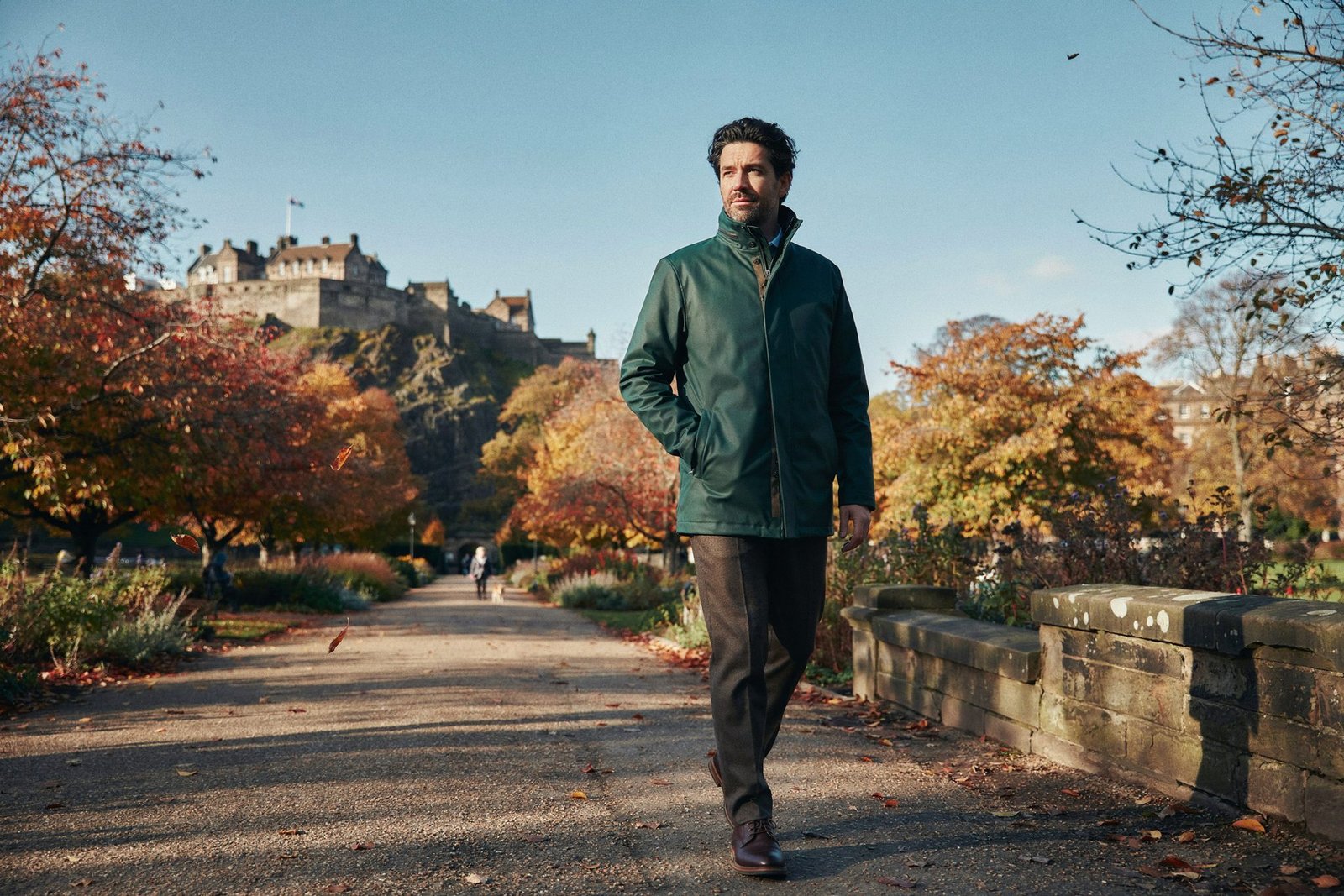 Adult walking through Princes Street Gardens in Edinburgh on a bright, cold morning with the castle behind, feeling well after a flu vaccine